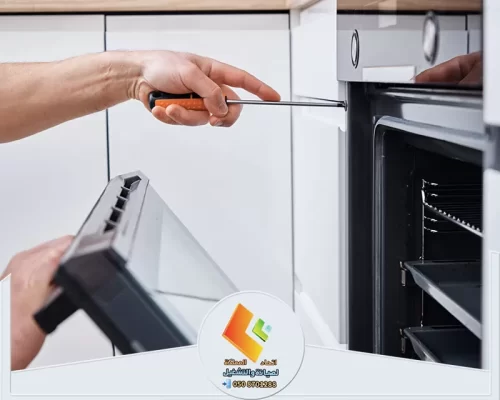 إصلاح باب الفرن باستخدام أدوات يدوية داخل مطبخ حديث.