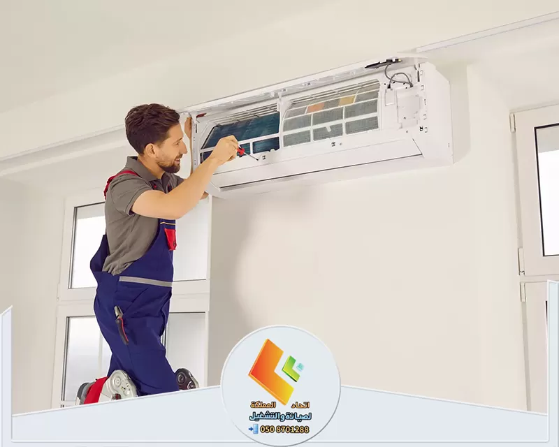 فك وتركيب مكيفات بالرياض 0530613269 اتحاد المملكة فني يعمل على تنظيف وصيانة مكيف هواء مركب على الحائط، وهو يفتح الجزء الأمامي من المكيف للقيام بالصيانة.