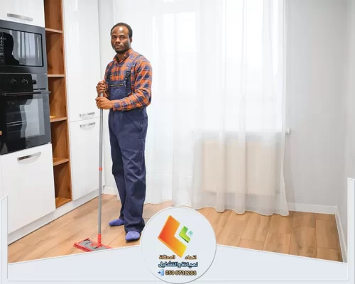 عامل تنظيف يمسك ممسحة أثناء تنظيف أرضية مطبخ حديث.