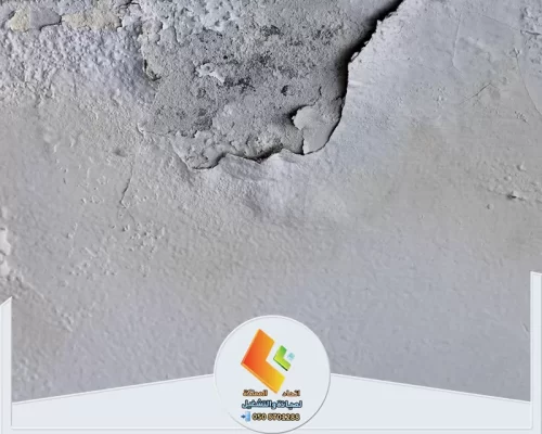 تقشر وتلف في طبقة المحارة على جدار خرساني مع تشققات واضحة تحتاج إلى ترميم ومعالجة للرطوبة.